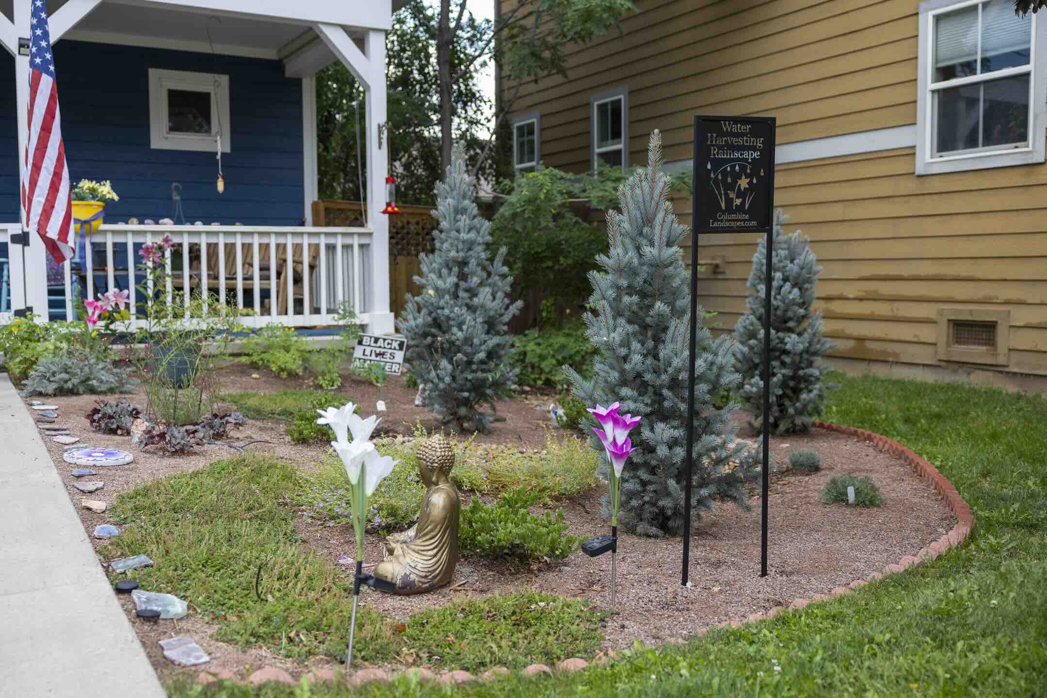 Water Harvesting Rainscape sign among blue spruce and rock mulch plantings at 3 Springs