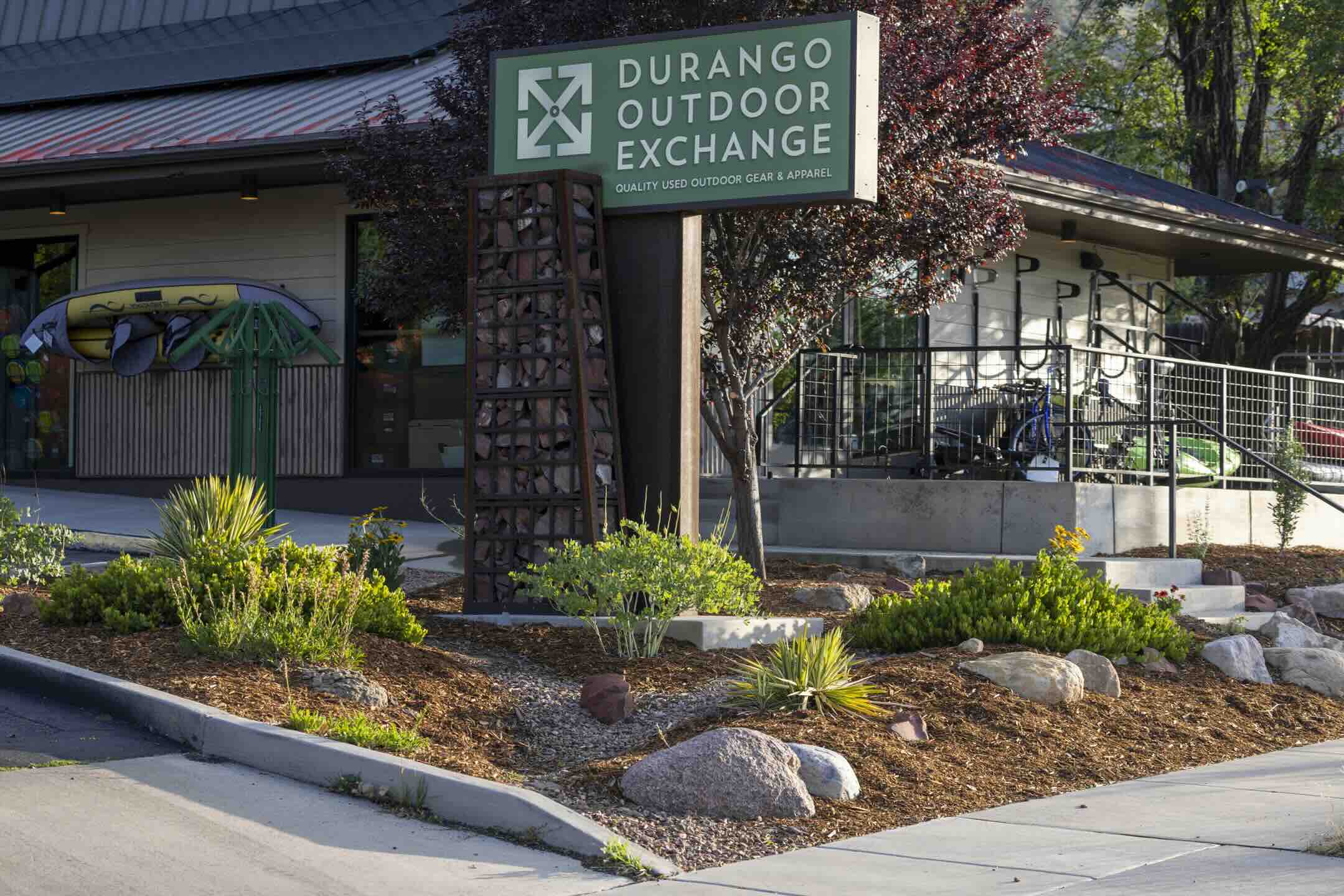 Drought-tolerant landscaping with boulders and native plants at the Durango Outdoor Exchange storefront sign