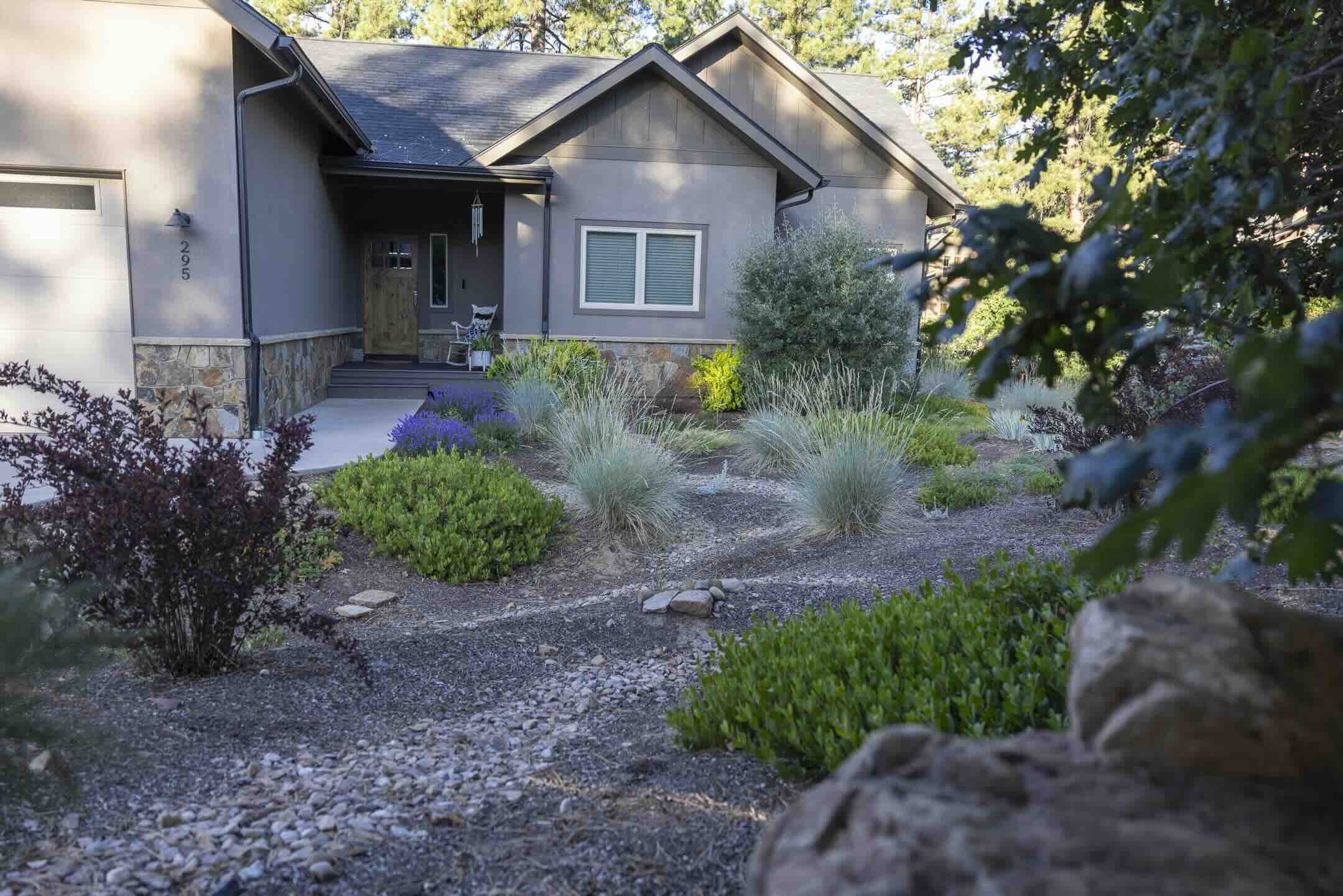Dry creek bed with river rock, ornamental grasses, and lavender along a Durango home's foundation