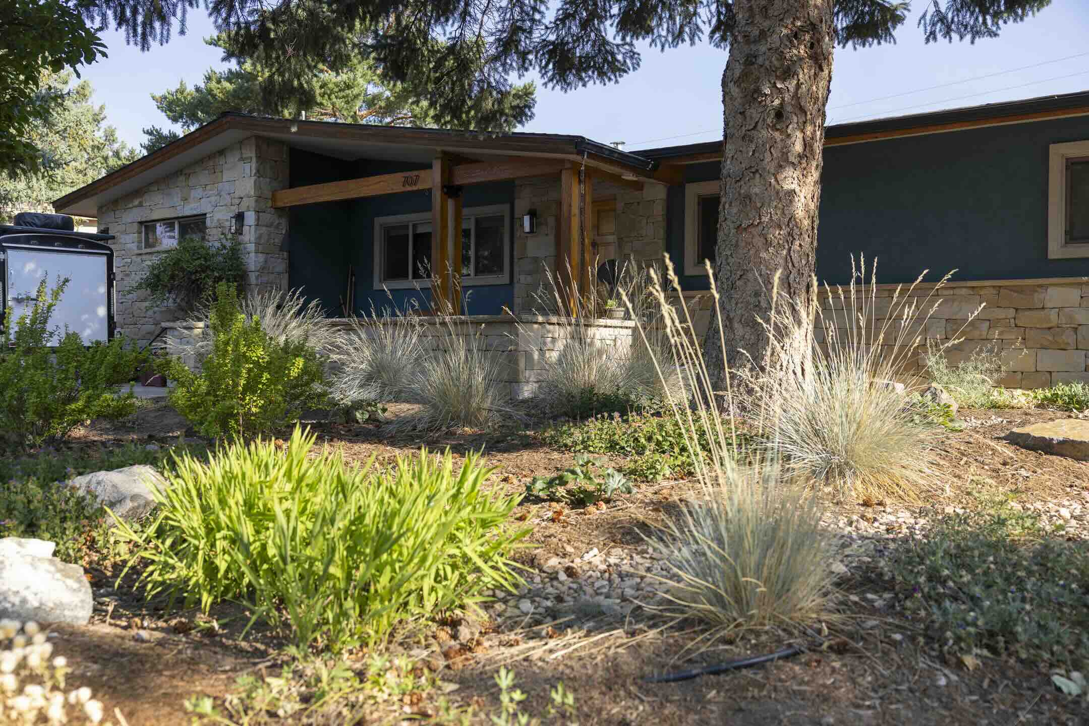Native grasses and mixed perennials along a stone-faced Durango home's front planting bed at Riverview